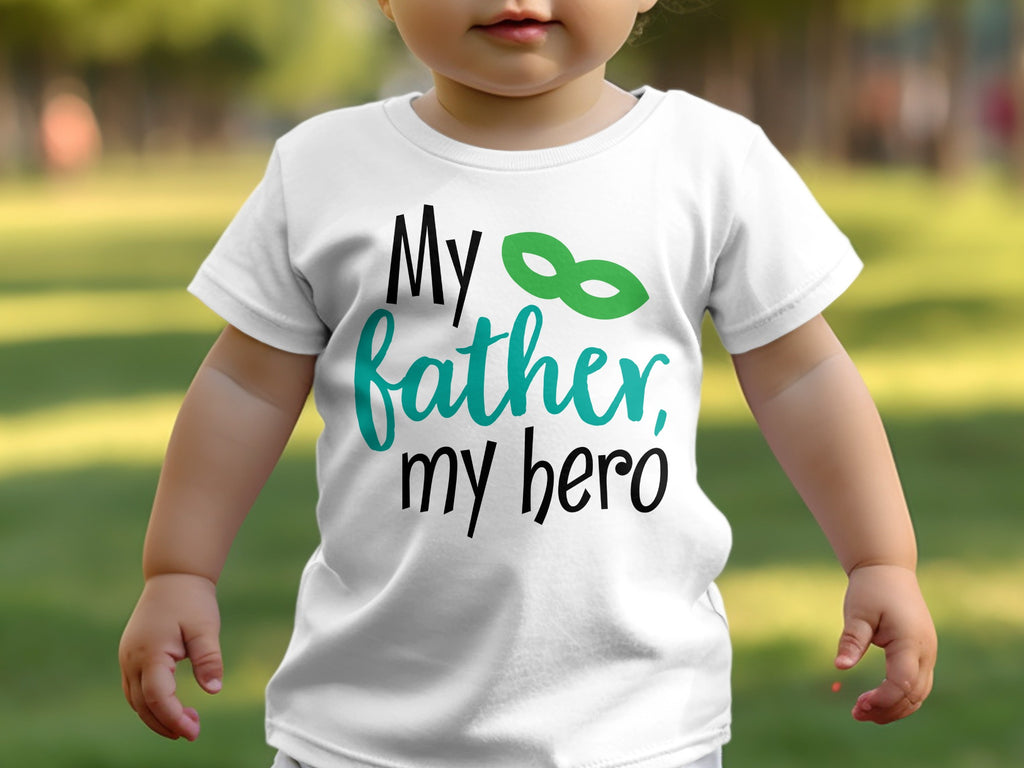 A young child wearing a white t-shirt printed with the text My father, my hero and a green mask graphic.