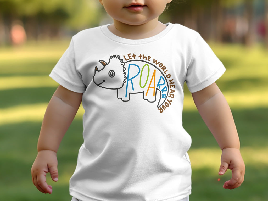 A young child wearing a white t-shirt featuring a cartoon triceratops and the text LET THE WORLD HEAR YOUR ROAR.