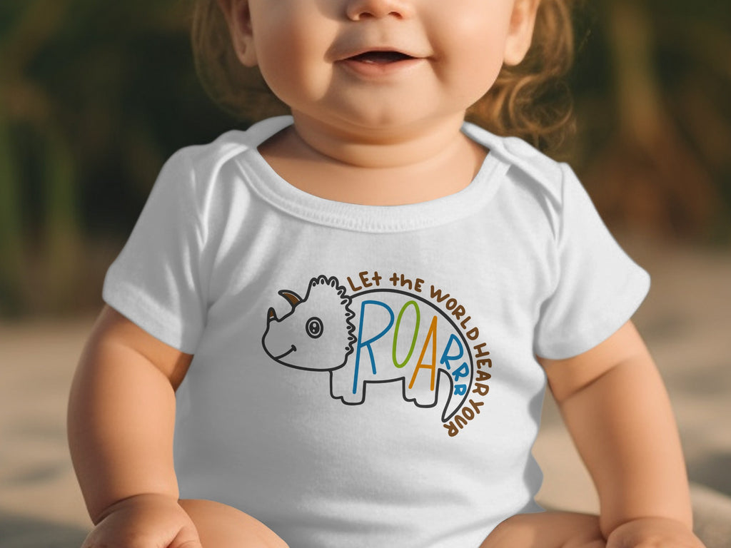 A baby wearing a white short-sleeve bodysuit with a triceratops outline and dinosaur text reading let the world hear your roar.