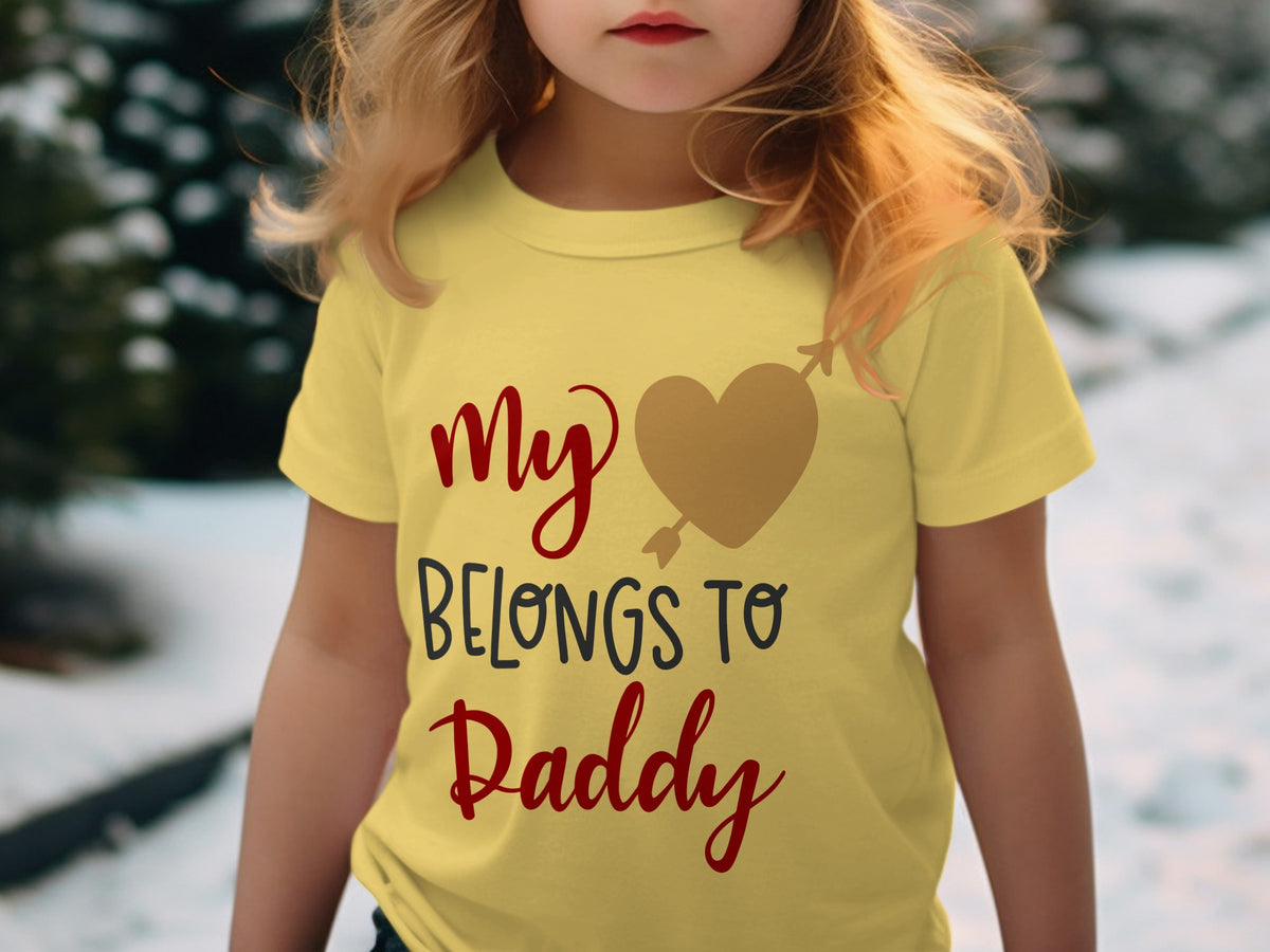 A child wears a yellow t-shirt printed with the red and black text My heart belongs to Daddy.