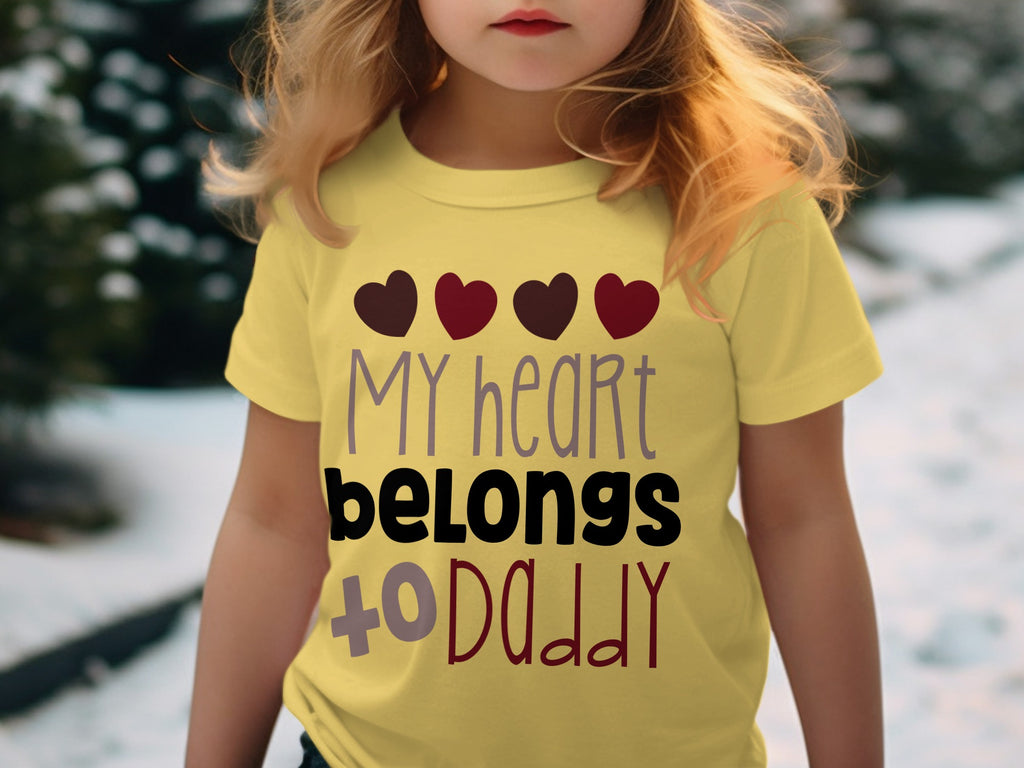 A young child wears a yellow t-shirt printed with four hearts and the text My heart belongs to Daddy.