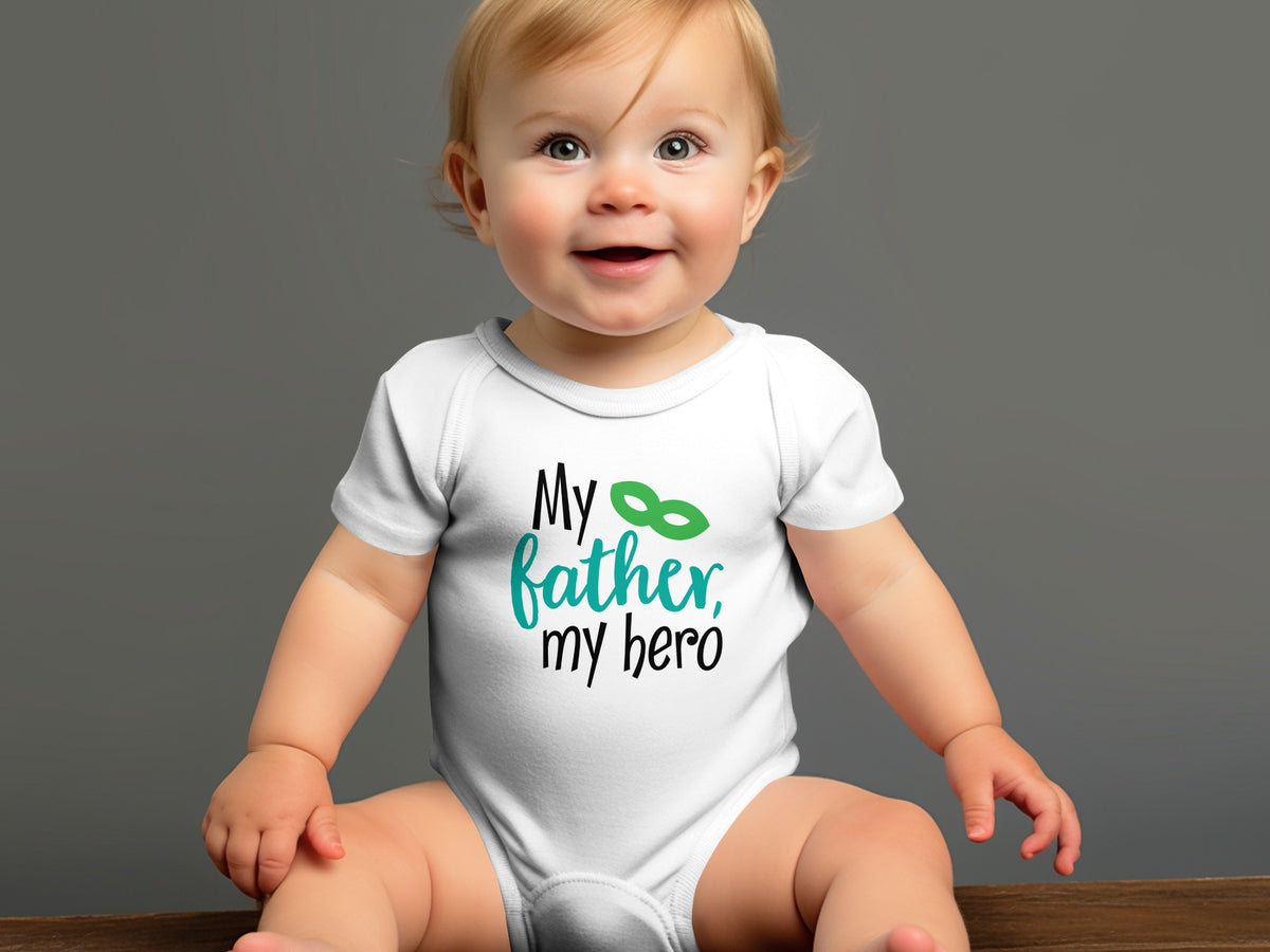 A smiling baby wears a white bodysuit printed with the words My father, my hero.