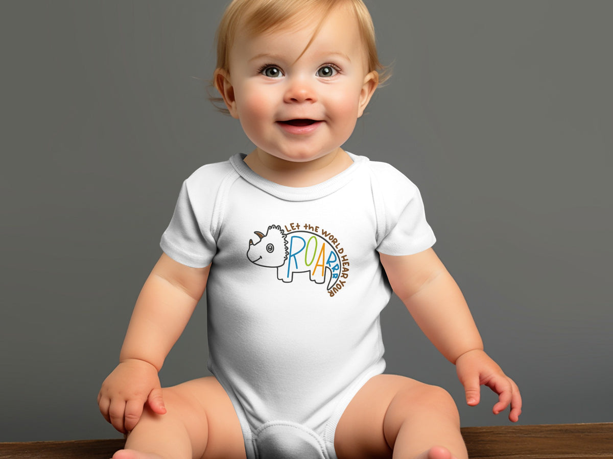 A smiling baby sits wearing a white baby bodysuit featuring a triceratops graphic and text.