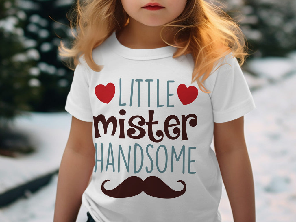 A child wearing a white t-shirt featuring the text "LITTLE mister HANDSOME" flanked by red hearts and a mustache.