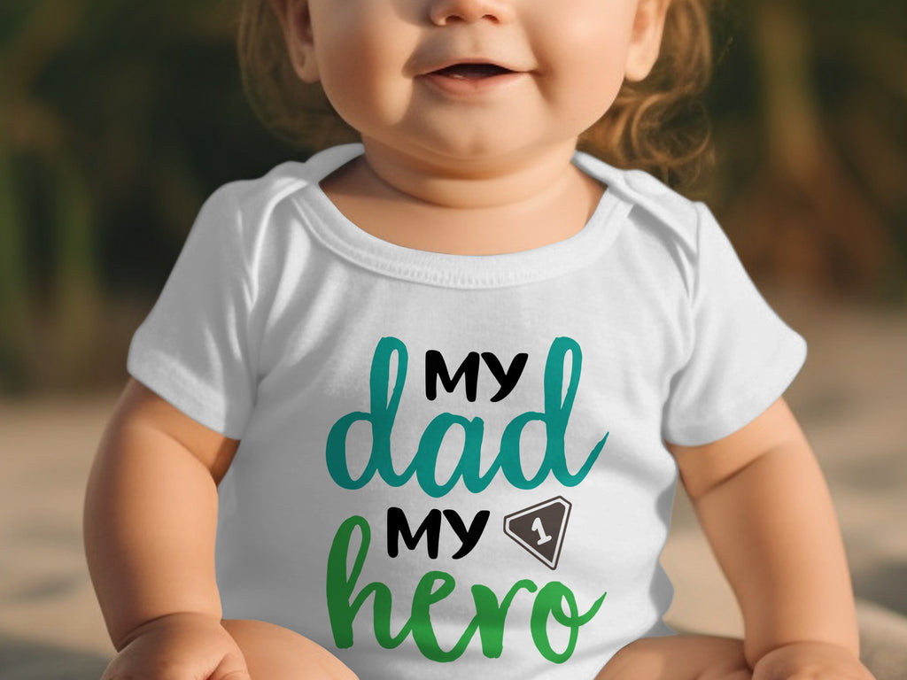 A baby wearing a white bodysuit with the text My Dad My Hero printed on the chest.