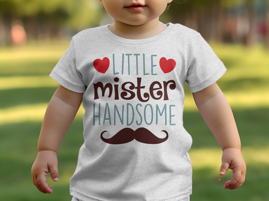 A baby wearing a heather grey t-shirt featuring the text Little mister HANDSOME and a mustache graphic.