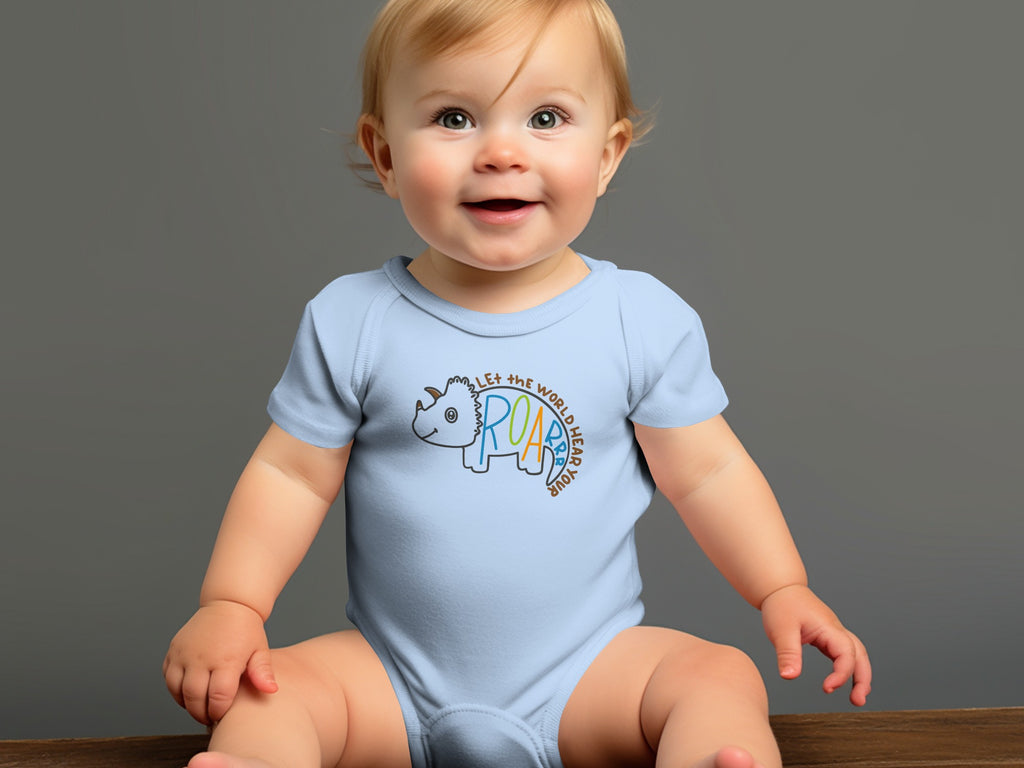A smiling baby sits wearing a light blue short-sleeve onesie featuring a dinosaur graphic and text.