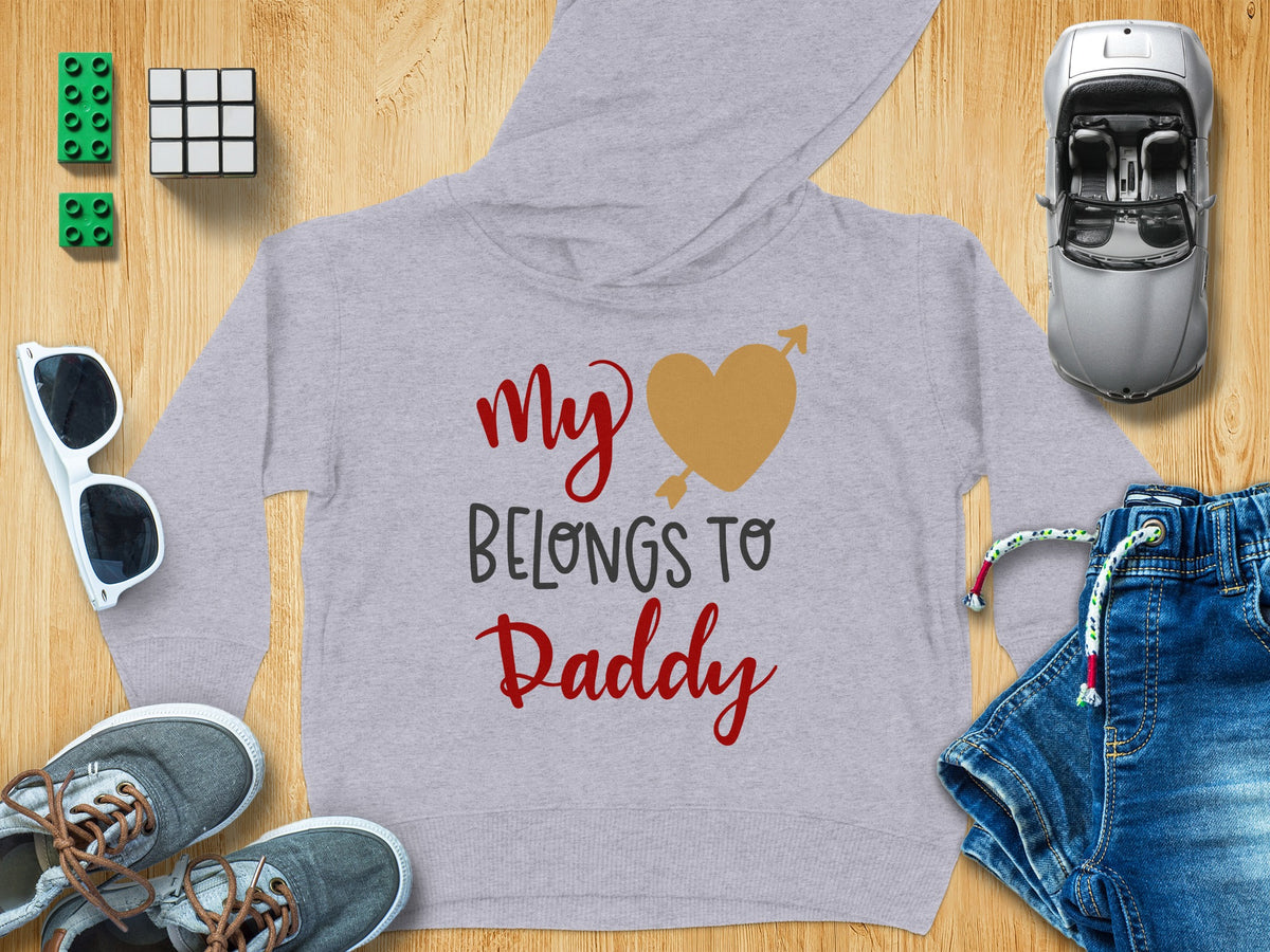Gray children hoodie with the text "My [heart] Belongs to Daddy" surrounded by toys on a wooden background.